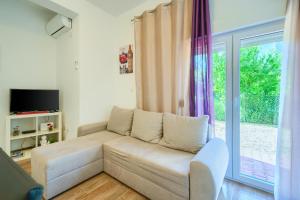 a living room with a couch and a sliding glass door at Cozy New Apartments with Private Pool Podstrana in Podstrana