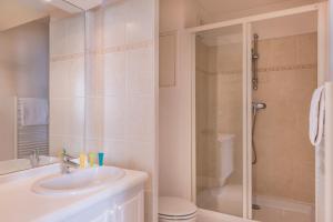 La salle de bains blanche est pourvue d'un lavabo et d'une douche. dans l'établissement Résidence du Grand Hôtel, au Plessis-Robinson