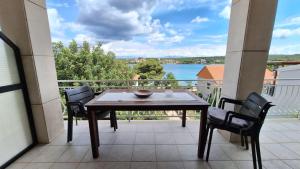 een tafel en stoelen op een balkon met uitzicht op het water bij Ceratonia Apartments in Lovište
