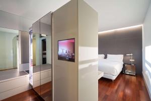 1 dormitorio con cama blanca y espejo en NH Collection Barcelona Constanza en Barcelona