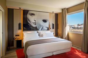 a bedroom with a large bed with a poster of a woman at NH Collection Madrid Suecia in Madrid