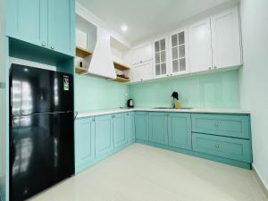 een keuken met blauwe kasten en een zwarte koelkast bij Moon homestay, apartment Hue in Hue