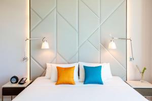 um quarto com uma cama branca e almofadas coloridas em Avani Cancun Airport -previously NH Cancun Airport- em Cancún