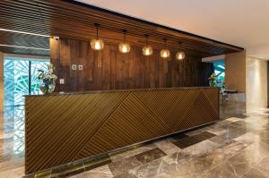 a lobby with a large wooden wall with lights at NH Collection Merida Paseo Montejo in Mérida