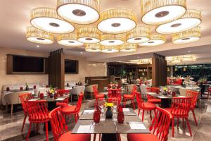 a restaurant with red chairs and tables and a large chandelier at NH Collection Merida Paseo Montejo in Mérida