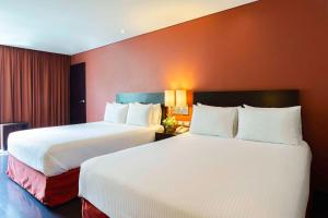 2 Betten in einem Hotelzimmer mit roten Wänden in der Unterkunft NH Puebla Centro Histórico in Puebla