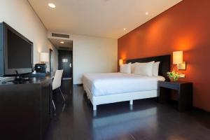 ein Hotelzimmer mit einem Bett und einem Flachbild-TV in der Unterkunft NH Puebla Centro Histórico in Puebla