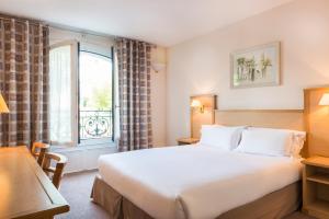 ein Hotelzimmer mit einem großen Bett und einem Fenster in der Unterkunft Résidence du Grand Hôtel in Le Plessis-Robinson
