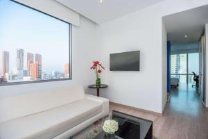 a living room with a white couch and a large window at NH Collection Royal Smartsuites in Barranquilla