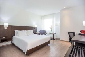 a hotel room with a bed and a desk and a desk at NH Collection Royal Smartsuites in Barranquilla
