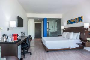a hotel room with a large bed and a desk at NH Collection Royal Smartsuites in Barranquilla