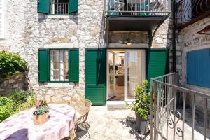 un patio con un tavolo e porte verdi e un edificio di Casa Batana by Briskva a Vrsar