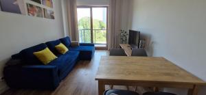 Letnicka Apart في غدانسك: غرفة معيشة مع أريكة زرقاء وطاولة خشبية
