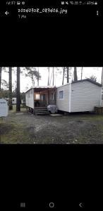 una piccola roulotte bianca con una casa in un campo di Vacances contis plage a Saint-Julien-en-Born