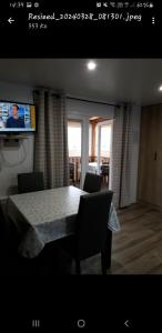 una sala da pranzo con tavolo, sedie e TV di Vacances contis plage a Saint-Julien-en-Born