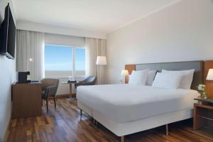 um quarto de hotel com uma grande cama branca e uma janela em NH Montevideo Columbia em Montevidéu