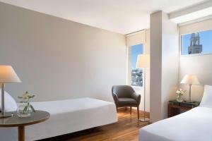 una habitación de hotel con 2 camas y una silla en NH Montevideo Columbia, en Montevideo