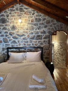una cama en una habitación con una pared de piedra en Ogustus Four Seasons Residence, en Koupiá