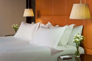 a bed with white pillows on it with two lamps at NH Collection Buenos Aires Lancaster in Buenos Aires