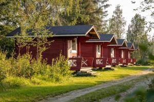 a row of red cabins in a forest at Arctic River Resort in Ivalo