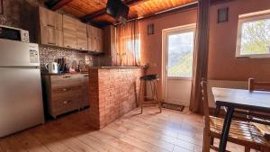 een keuken met een koelkast, een tafel en een raam bij Cottage Gudauri in Goedaoeri