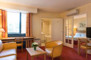 une chambre d'hôtel avec un lit et un salon dans l'établissement Résidence du Grand Hôtel, au Plessis-Robinson