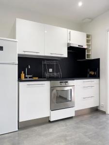 a kitchen with white cabinets and a stainless steel oven at Les Cerisiers RdC Lumineux, Jardin, Terrasse in Baisieux