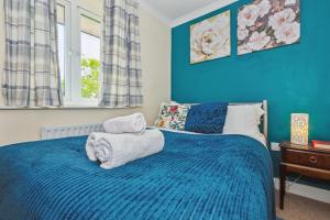 Un dormitorio azul con una cama con toallas. en Global Boutique Relocation Ltd 2Bed -free parking en Hatfield