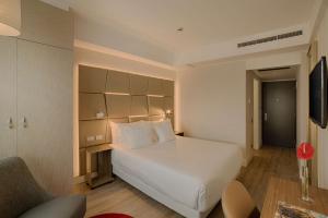 um quarto de hotel com uma cama branca e uma cadeira em NH Collection Roma Centro em Roma
