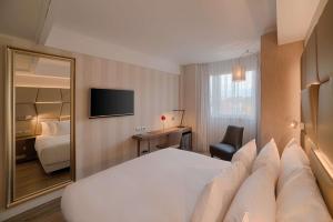 um quarto de hotel com uma cama branca e um espelho em NH Collection Roma Centro em Roma