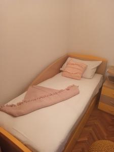 a small bed with white sheets and a pink blanket at Apartmani Mislav in Slatine