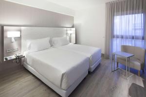 Un dormitorio con una gran cama blanca y una ventana en NH Milano Congress Centre, en Assago