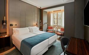 um quarto de hotel com uma cama grande e uma mesa em NH Collection Madrid Gran Vía em Madri