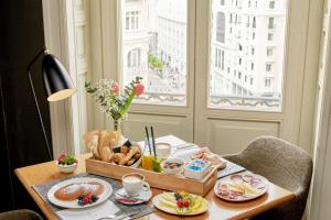 a table with a tray of food and a window at NH Collection Madrid Gran Vía in Madrid