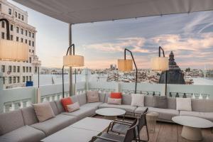 un patio all'ultimo piano con divano, tavoli e vista di NH Collection Madrid Gran Vía a Madrid