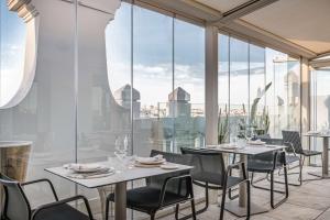 a restaurant with tables and chairs and glass windows at NH Collection Madrid Gran Vía in Madrid