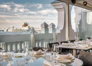a table with wine glasses and plates on a balcony at NH Collection Madrid Gran Vía in Madrid +37 photos