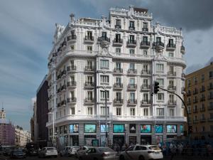 a tall white building on a city street with cars at NH Collection Madrid Gran Vía in Madrid