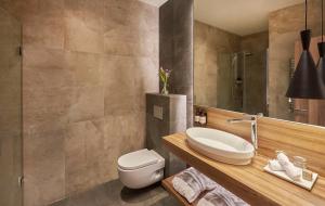 a bathroom with a toilet and a sink and a mirror at NH Collection Madrid Gran Vía in Madrid