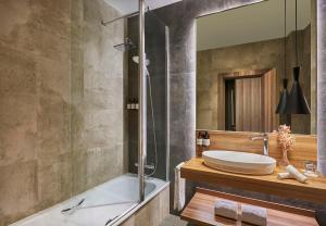 a bathroom with a tub and a sink and a mirror at NH Collection Madrid Gran Vía in Madrid