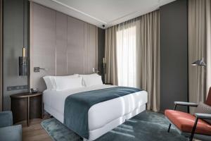 a bedroom with a large white bed and a chair at NH Collection Madrid Gran Vía in Madrid