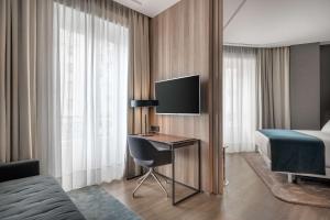 a hotel room with a bed and a desk with a television at NH Collection Madrid Gran Vía in Madrid