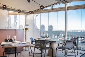 a dining room with a table and chairs and large windows at NH Collection Madrid Gran Vía in Madrid