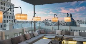 a rooftop patio with a couch and tables on a building at NH Collection Madrid Gran Vía in Madrid