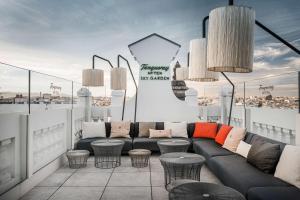 a rooftop patio with a couch and some tables and chairs at NH Collection Madrid Gran Vía in Madrid