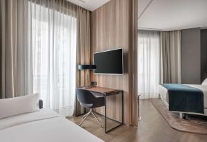 a hotel room with a bed and a desk with a television at NH Collection Madrid Gran Vía in Madrid
