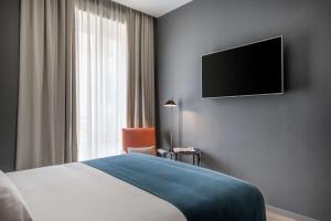 a hotel room with a bed and a flat screen tv at NH Collection Madrid Gran Vía in Madrid