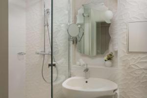 ein Bad mit einem Waschbecken und einer Dusche mit einem Spiegel in der Unterkunft NH Paris Gare de l'Est in Paris