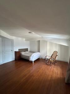 a bedroom with a bed and a chair in it at La Maison des Chanoines in Verdun-sur-Meuse