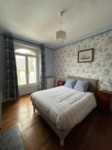 a bedroom with a bed with blue walls and a window at La Maison des Chanoines in Verdun-sur-Meuse